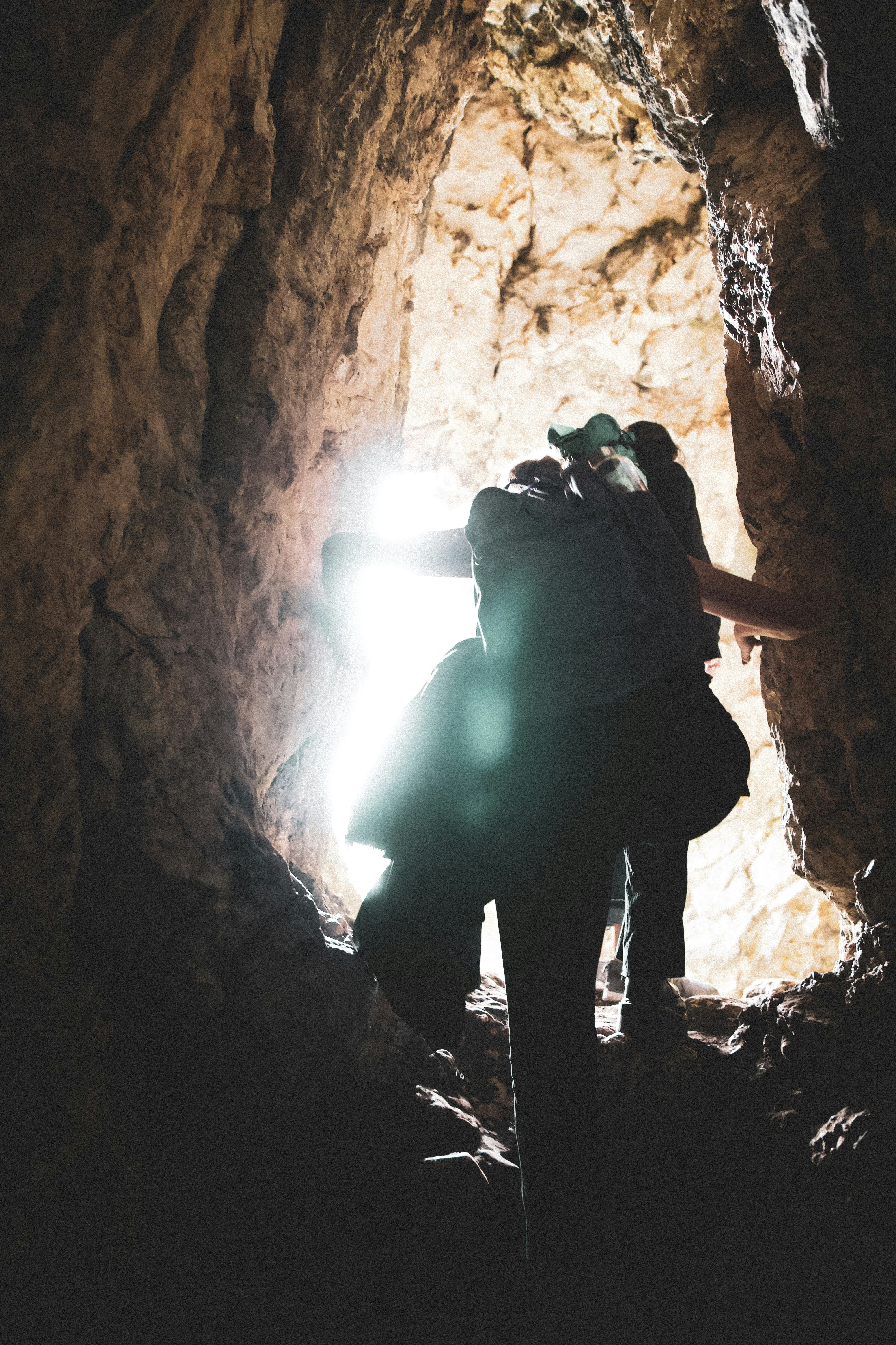 man in black backpack standing inside cave